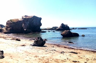 Rocks on beach against clear sky