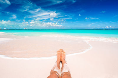 Low section of person on beach against sky