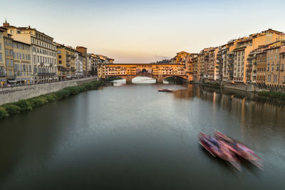Ponte vecchio over arno river during sunset in city