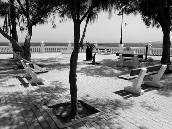 Empty bench by swimming pool against sky