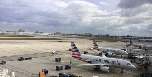 Airplanes on airport runway against cloudy sky