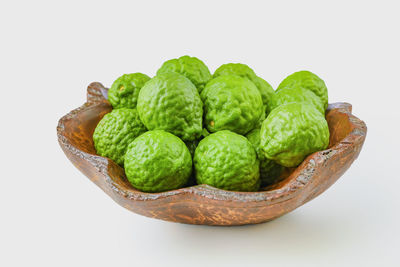 Close-up of green fruit on table against white background