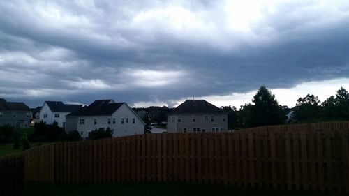 Houses on landscape against cloudy sky