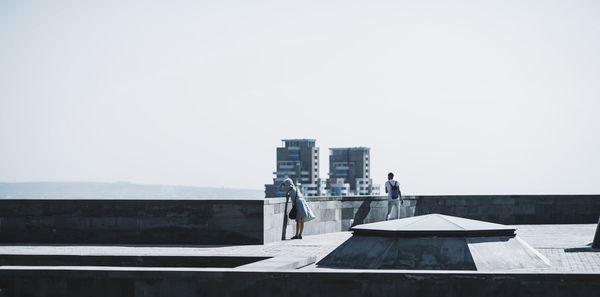 People on building terrace against clear sky