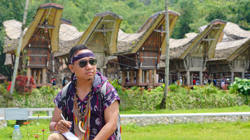 Portrait of young man wearing sunglasses standing against trees