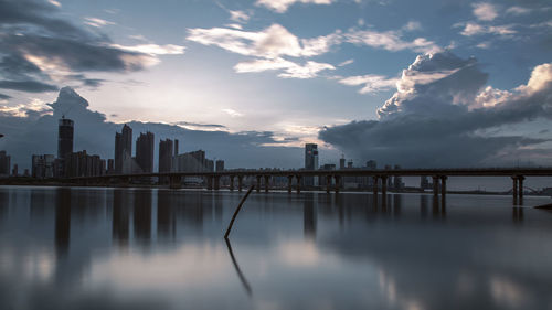 City at waterfront against cloudy sky