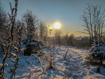 Snow covered field against sky during sunset