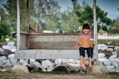 Little girl sitting and reading a book at a wooden gazebo outdoors