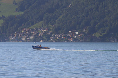 Boat sailing on sea against mountain