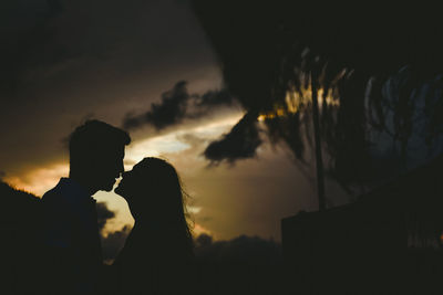 Silhouette couple embracing against sky during sunset