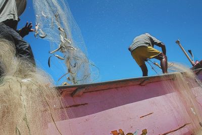 Low angle view of men holding fish in nets on wall