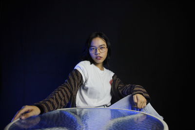 Portrait of young woman sitting against wall