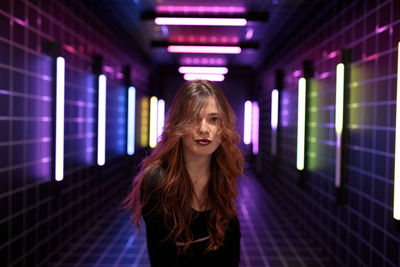 Portrait of young woman standing in city at night