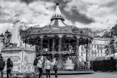 People at amusement park against sky