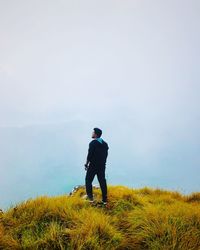 Rear view of man standing on field against sky