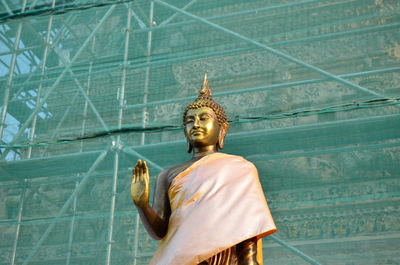 Buddha statue against scaffolding on building