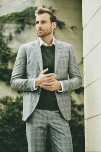 Young businessman looking away while standing by wall