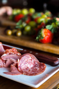 Close-up of meat and knife on cutting board at table