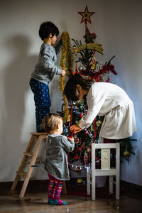 Children decorating christmas tree at home