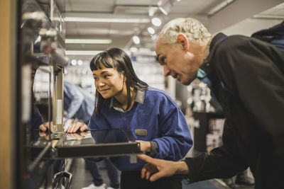 Saleswoman and mature customer looking at oven while standing in electronics store