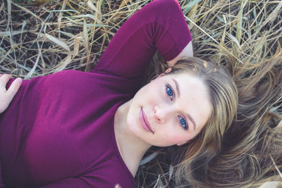 Directly above portrait of smiling beautiful woman lying on plants