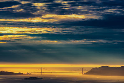 Low angle view of bridge against dramatic sky