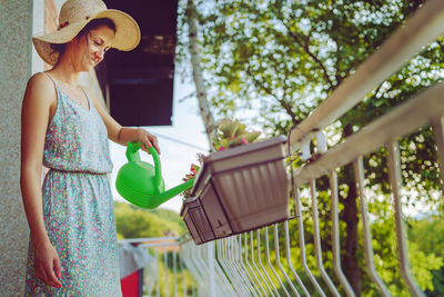 Woman holding umbrella standing by plants