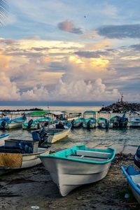 Boats in harbor against cloudy sky