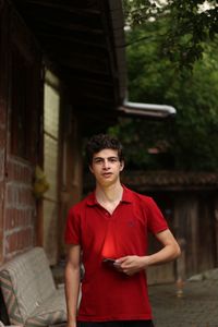 Portrait of young man standing against building