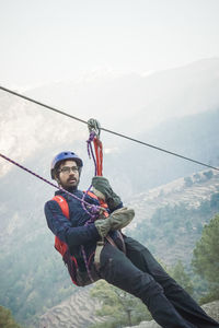 Man holding rope on mountain against sky