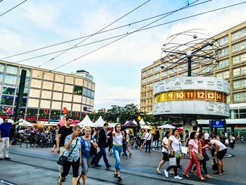 People walking at alexanderplatz against sky