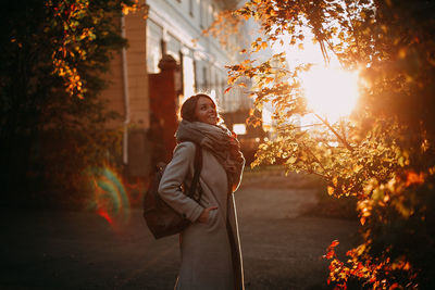 Young woman standing against sky during sunset