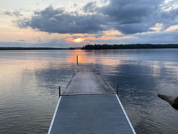 Pier on lake against sky during sunset