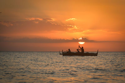 Silhouette people on boat on sea against sky during sunset