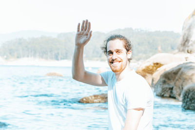 Young man with arms raised standing at beach