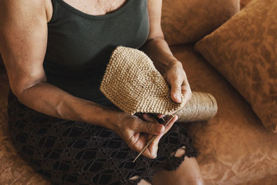 Midsection of woman knitting while sitting at home