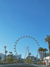 Low angle view of ferris wheel against clear blue sky