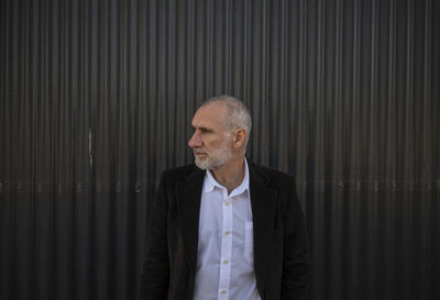 Portrait of adult man in suit against grey metal wall