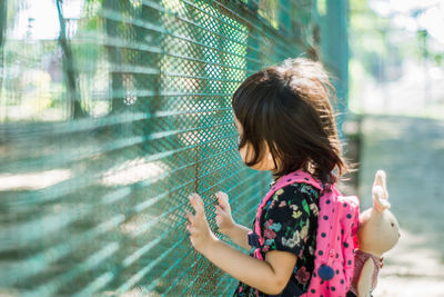 Girl standing against fence