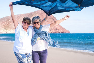Smiling women with scarf standing at beach