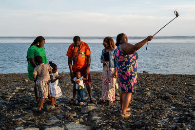 Rear view of people at beach against sky