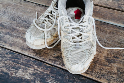 Low section of person wearing shoes on wooden floor