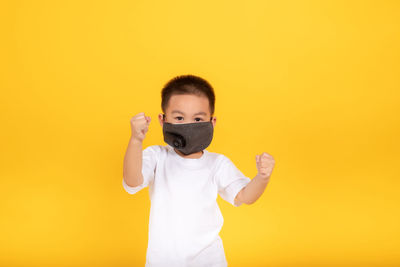 Portrait of boy standing against yellow background