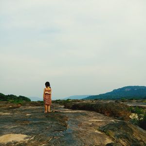 Rear view of man standing on mountain against sky