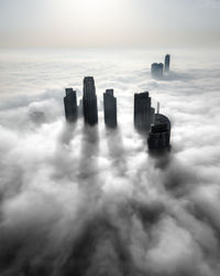 Aerial view of buildings against sky in city, covered by an early morning fog