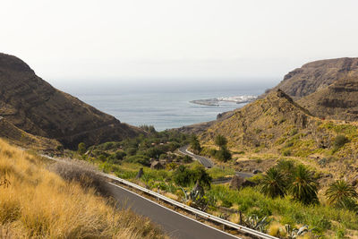 Scenic view of road by sea against sky