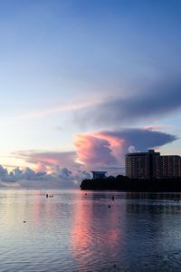 Scenic view of sea by buildings against sky during sunset