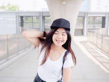 Portrait of young woman standing against building