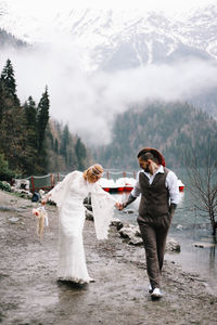 A loving married couple the bride and groom in suits celebrate wedding near the mountains and water