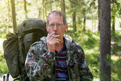 Portrait of mature man smoking cigarette in forest